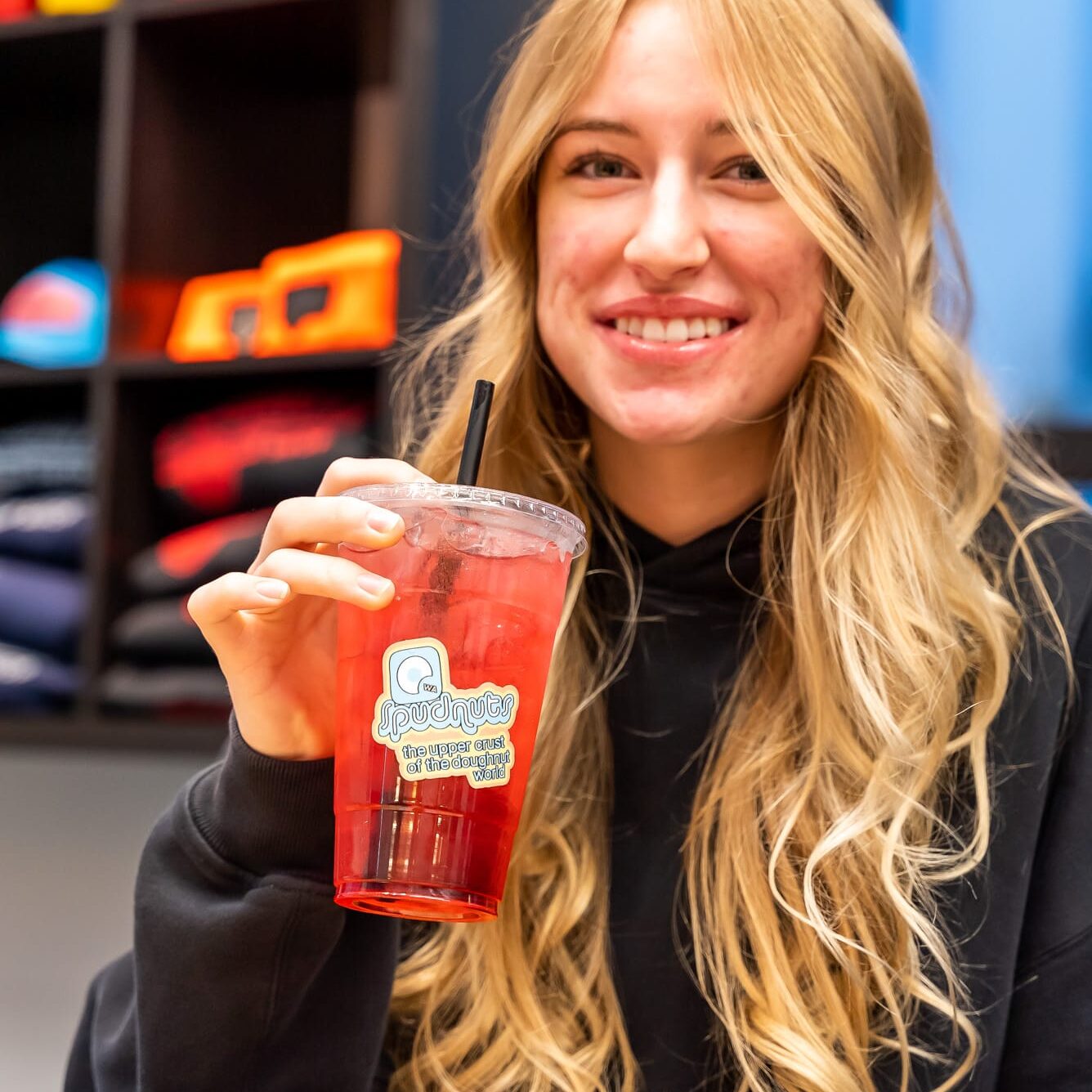 woman holding a drink while enjoying a spudnut